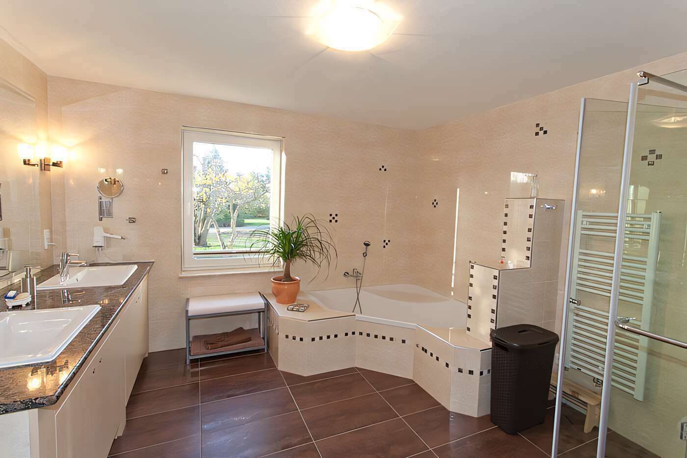 Das große Bad des Ferienhauses mit Dusche, Eckbadewanne, Waschmaschine und Wäschetrockner im Erdgeschoss